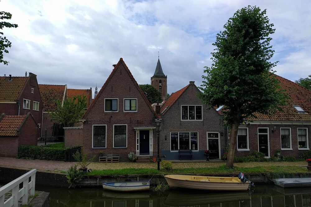 Grachtje in Monnickendam met historische huizen, bootjes en op de achtergrond een kerktoren